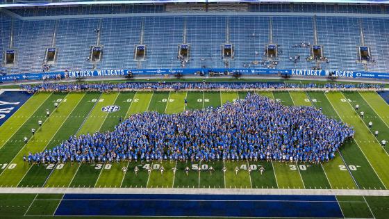 Thousands of students wearing blue arranged in the outline of the state of Kentucky on Kroger Field