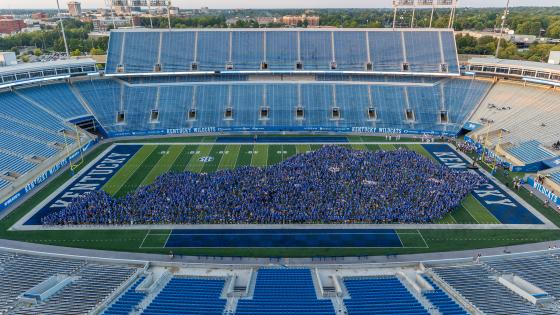 Thousands of students wearing blue arranged in the outline of the state of Kentucky on Kroger Field