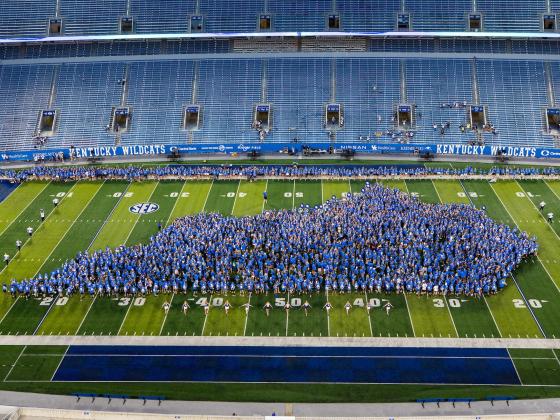 Thousands of students wearing blue arranged in the outline of the state of Kentucky on Kroger Field